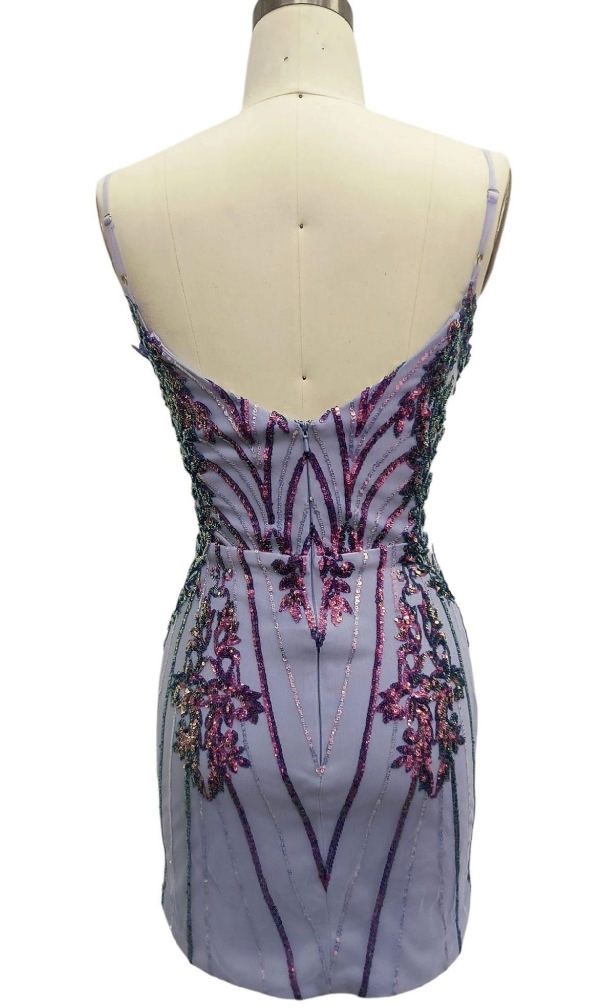 The Short Lilac Sequin Hoco Dress: 12439 is a light purple sleeveless homecoming dress displayed on a mannequin, with intricate pink and purple beaded and sequin embellishments on the back.